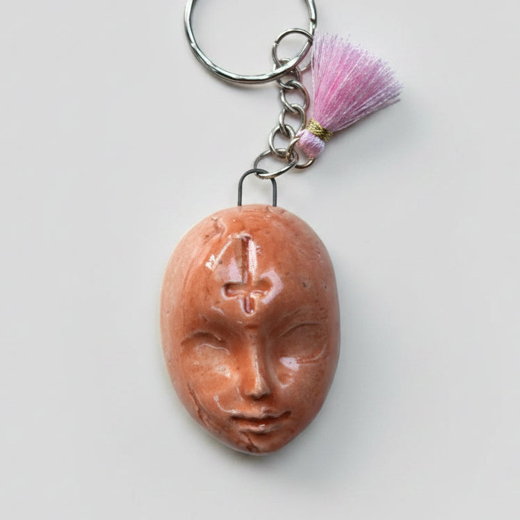 Doll Face Keyring – Enigmatic Ceramic Charm, 4 × 3 cm by Red Raven Pottery