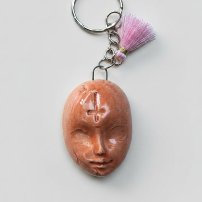 Doll Face Keyring – Enigmatic Ceramic Charm, 4 × 3 cm by Red Raven Pottery
